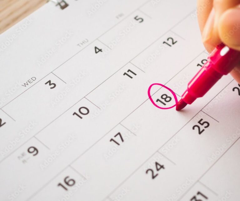 A close-up of a hand circling the date "18" on a calendar with a pink marker. The calendar shows dates from the 7th to the 25th, with visible days of the week from Tuesday to Thursday. The focus is on the act of marking the 18th.